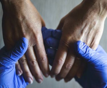 The hands of a doctor welcomes those of a patient as a sign of encouragement