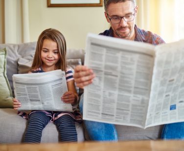 Shot of a father and daughter reading the newspaper